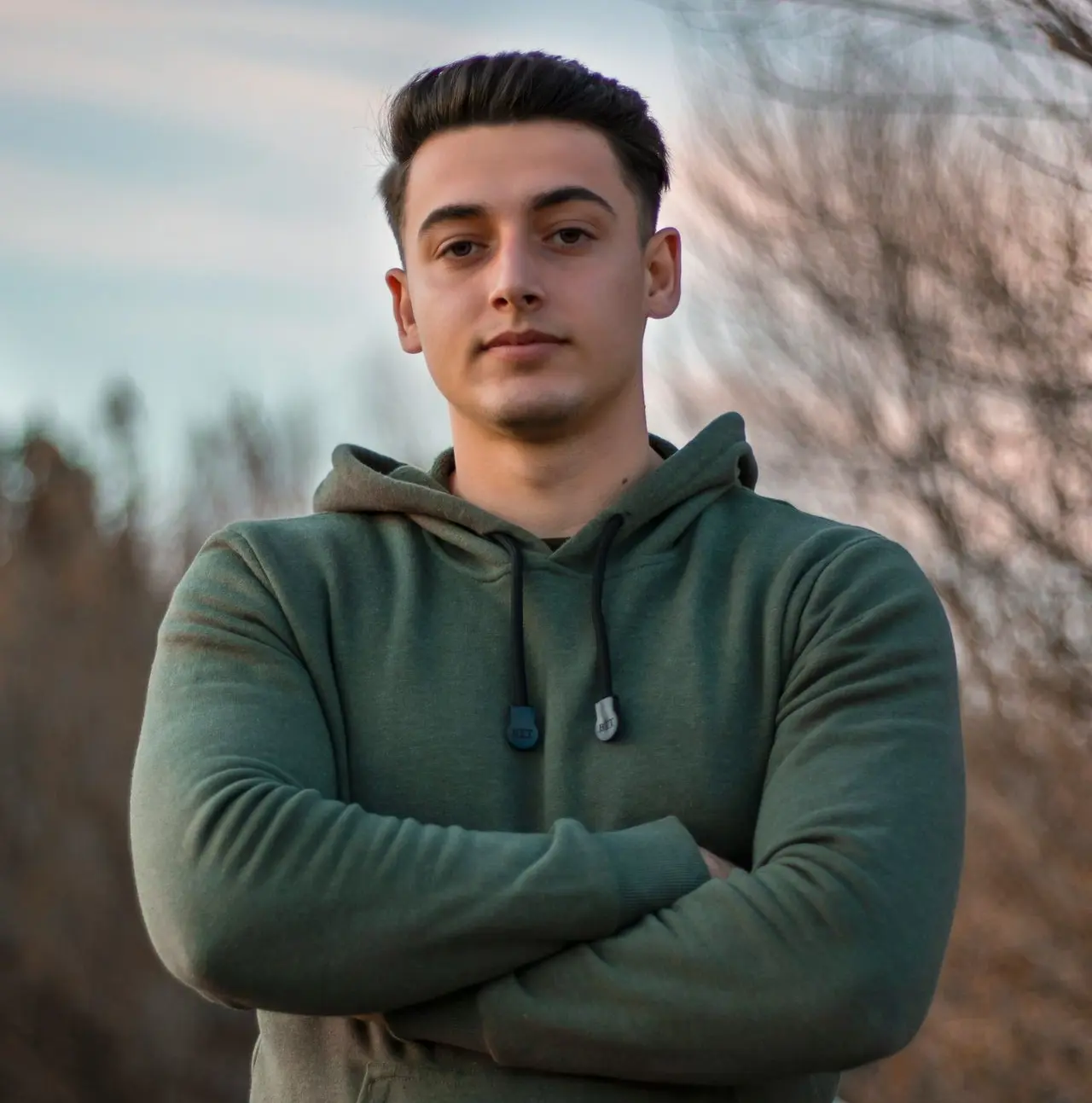 man in green hoodie standing on blue metal railings during daytime