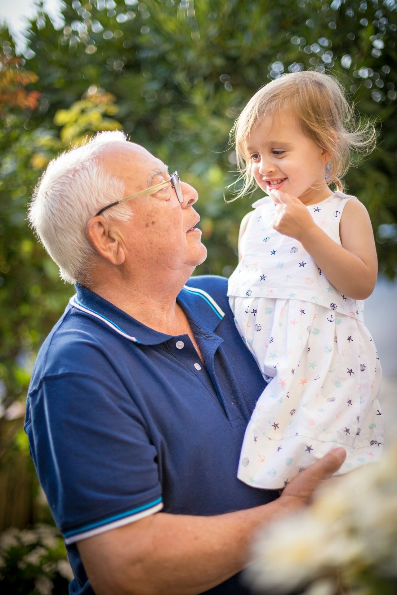 Abuelo conversando de cerca y sonriendo con su nieta
